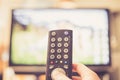 Male hand is holding TV remote control, streaming on a smart TV Royalty Free Stock Photo