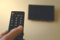 TV remote control in male hand in front of widescreen TV set with blank screen. Royalty Free Stock Photo