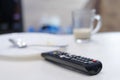 TV remote control on table, in kitchen next empty plate and cup, end breakfast Royalty Free Stock Photo