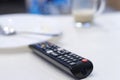 TV remote control on table, in kitchen next empty plate and cup, end breakfast Royalty Free Stock Photo