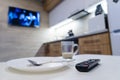 TV remote control on table, in kitchen next empty plate and cup, end breakfast Royalty Free Stock Photo