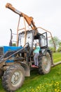 A girl stands on the running board of a tractor.