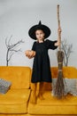 Tween age girl dressed as a witch holding a broom, posing for a photo Royalty Free Stock Photo