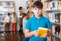 Tween boy with book in school library Royalty Free Stock Photo