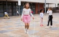 Tween girl in pink skirt jumping rope in schoolyard during recess Royalty Free Stock Photo