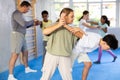 Tween girl practicing armlock in sparring with boy during self-defense classes