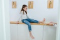Tween girl sitting on a corridor shelf, her feet being tickled by her mom