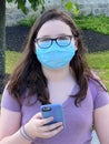 Tween Girl Wearing Surgical Mask Outdoors Holding Mobile Phone Royalty Free Stock Photo