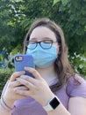 Tween Girl Wearing Surgical Mask Outdoors Texting On her Mobile Phone Royalty Free Stock Photo