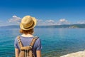 Tween tourist girl in hat and backpack admiring beautiful landscape of lake Baikal from waterfront of Listvyanka village in sunny Royalty Free Stock Photo