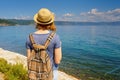 Tween tourist girl in hat and backpack admiring beautiful landscape of lake Baikal from waterfront of Listvyanka village in sunny Royalty Free Stock Photo