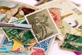 Tweezers holding a UK postage stamp with Queen Elizabeth 2 side portrait collection of stamps in the background Royalty Free Stock Photo