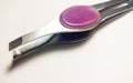 Tweezers with purple handle on white background.