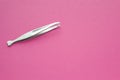 Tweezers stainless steel for women on pink background. Silver pincers for eyebrow plucking