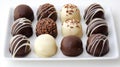 Luxurious chocolate truffles in dark, milk, and white varieties garnished with chocolate shavings, artfully arranged on crisp Royalty Free Stock Photo
