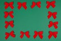 Red Cristmas bows on green background.