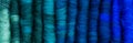 Twelve hand-made merino wool rolags, in colours from green to blue Royalty Free Stock Photo