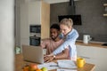 Young interracial couple using laptop together having breakfast at home Royalty Free Stock Photo