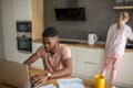 Young interracial couple using laptop together having breakfast at home Royalty Free Stock Photo