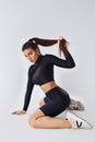 Twerk dancing. Sportive woman in black clothes in the studio against white background