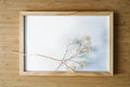 Twigs of gypsophila with soft shadows on an empty wooden picture frame, bamboo background, minimal still life as flat lay