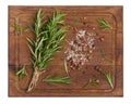 Twigs and leaves of rosemary, dry fruits of red, black and allspice and salt on a wooden cutting board, top view