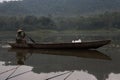 A fisherman, wooden boat, freshwater lake.