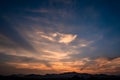 Twilight dramatic blue sky with white clouds and orange sunlight and silhouette of mountains. Royalty Free Stock Photo