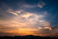 Twilight dramatic cloudy blue sky with orange sunlight and silhouette of mountains. Royalty Free Stock Photo