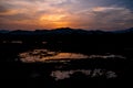 Twilight dramatic cloudy sky with orange sunlight and silhouette of mountains and swamp. Royalty Free Stock Photo