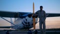 Twilight landscape with a male aviator standing beside a cropduster