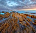 Twilight ocean coast with ribbed stratiform rock Royalty Free Stock Photo