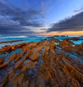 Twilight ocean coast with ribbed stratiform rock Royalty Free Stock Photo