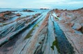 Twilight ocean coast with ribbed stratiform rock. Royalty Free Stock Photo