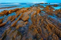 Twilight ocean coast with ribbed stratiform rock. Royalty Free Stock Photo