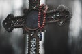 In the twilight a red rosary hangs on an old grave cross