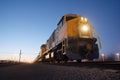 twilight scene of a freight train with illuminated headlamps