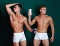 Twin athletes with serious faces wear underwear and hold shampoo