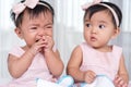 Twin babies in pink dress, one looking, one crying Royalty Free Stock Photo