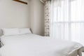 Twin beds and white blankets in a small white bedroom