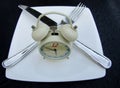 Twin bell alarm clock with fork and knife on white late