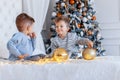 Twin brothers in front of the christmas tree with candles and gifts. love, happiness and big family concept Royalty Free Stock Photo