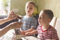 Twin brothers helping her mother to grind coffee