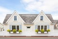 twin dormers with window boxes on a whitewashed cape cod facade
