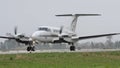 Twin engine turboprop airplane taxiing on the military base runway to take off