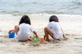 Twin girls while playing beach toys and sitting on a beach sand with white sand and waves Royalty Free Stock Photo