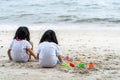 Twin girls while playing beach toys and sitting on a beach sand with white sand and waves Royalty Free Stock Photo