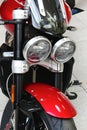 Twin round headlights and part of front mask of british motorcycle Triumph Rocket 3 GT in red and white colour