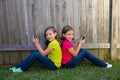 Twin sister girls playing smartphone sitting on backyard lawn