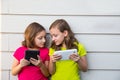 Twin sister girls playing with tablet pc happy on white wall Royalty Free Stock Photo